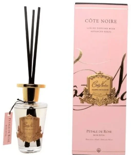 Difusor de aromas Côte Noire com varetas pretas, tampa dourada e caixa em tom rosa, aroma pétala de rosa.